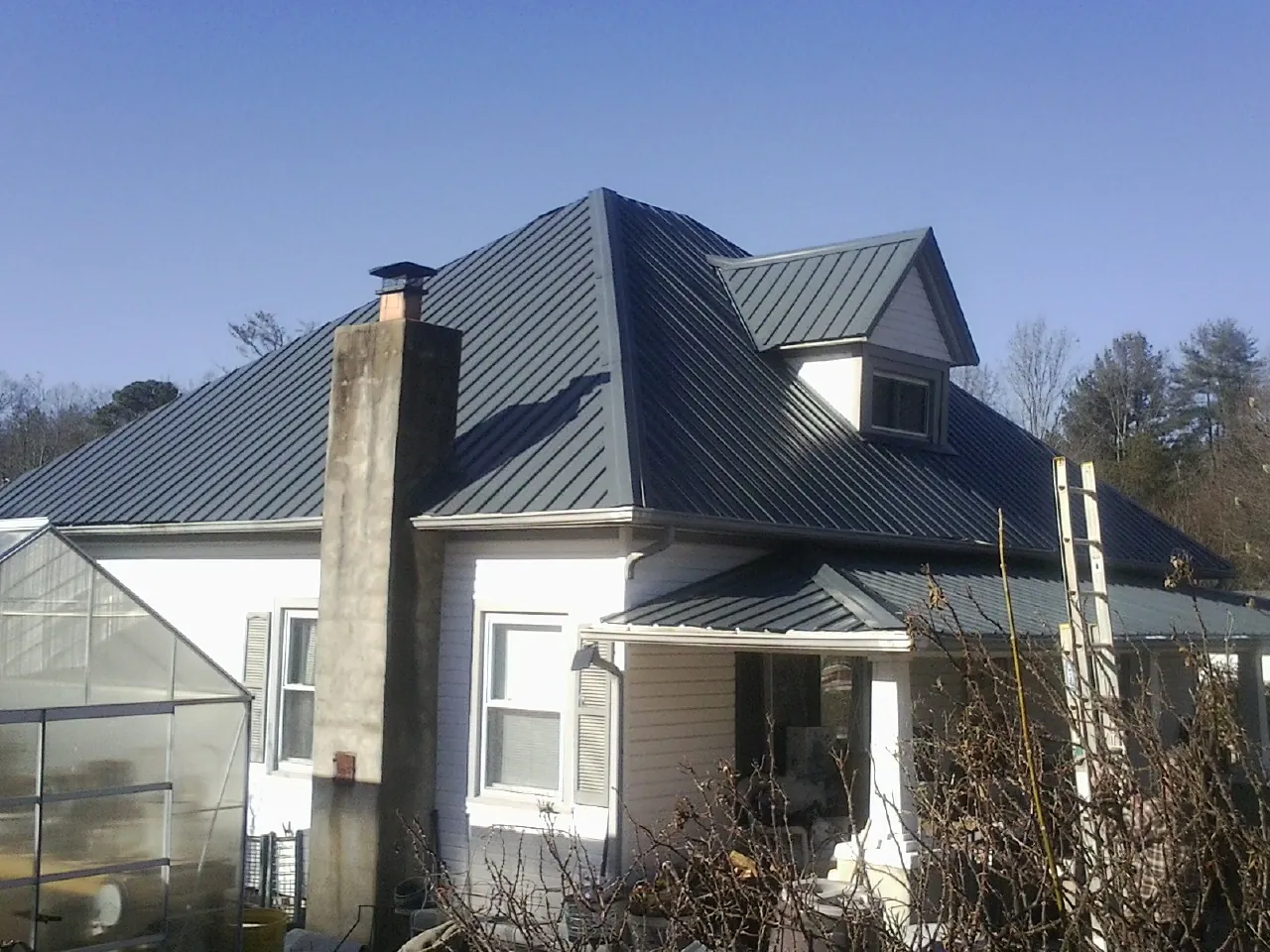 Dark blue standing seam metal roof on a white farmhouse with dormer — Slate & Tile Roof Repair by Roofing Brothers in Mashpee