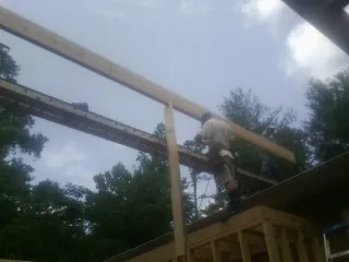 Carpenter setting a ridge beam over a new addition frame — Ice Dam Removal by Roofing Brothers in Mashpee
