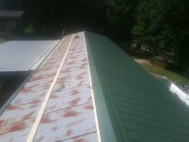 Old rusted panels beside newly installed green metal roofing — Wind Damage Roof Repair by Roofing Brothers in Mashpee