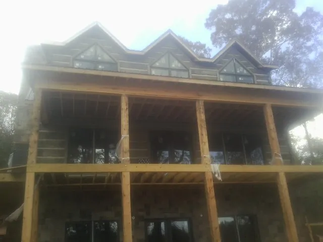 Dormers and porch framing on a large log home under construction — Roof Coating work by our crew in Mashpee