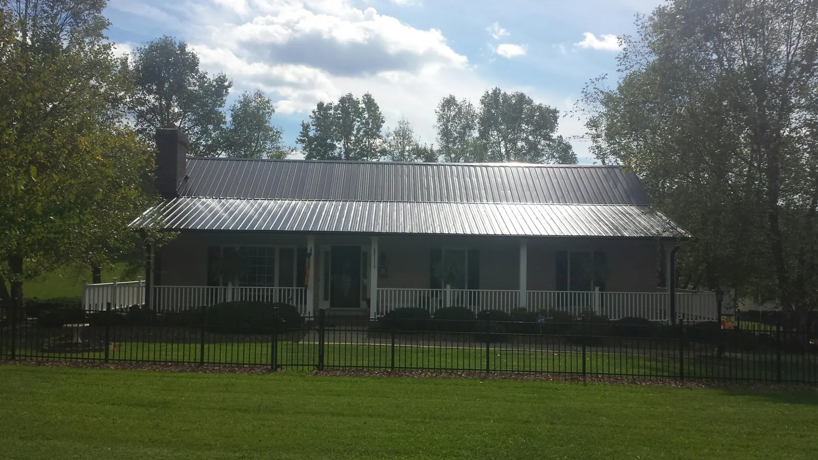 Gray metal roof on a brick ranch with a full width front porch — Gutter Guard Installation work by our crew in Mashpee